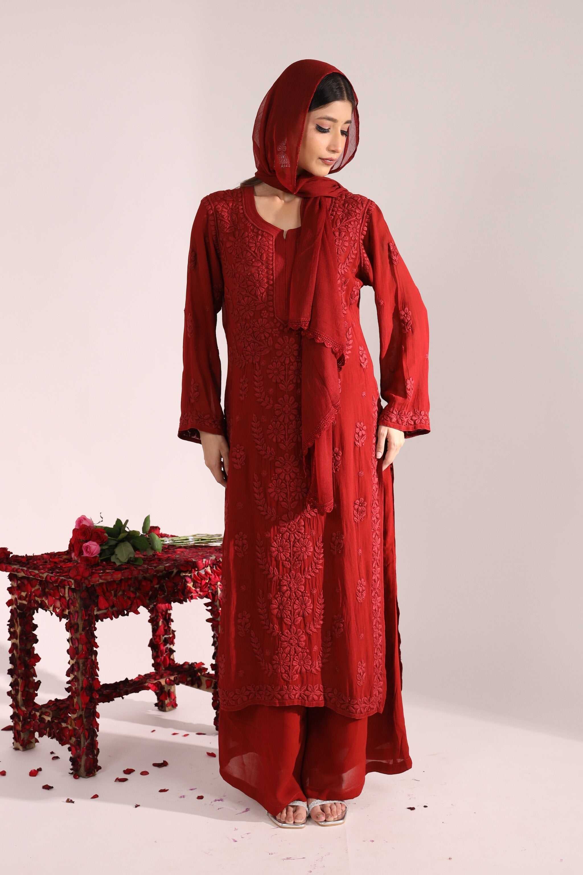 Woman wearing a red traditional chikankari bridal suit naina from sitara collection with a matching dupatta on a white background