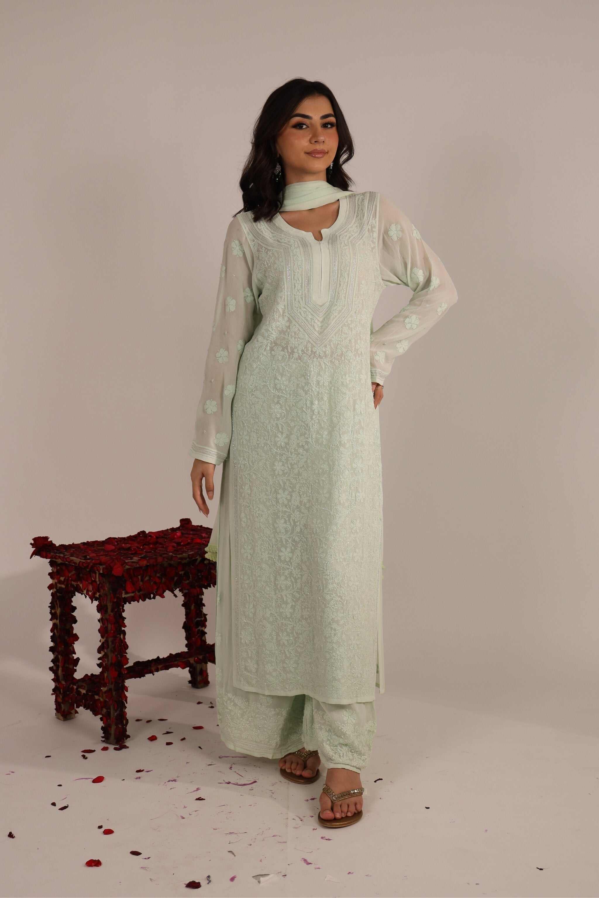 Woman wearing a light green chikankari kurta set with chiffon dupatta against a plain background