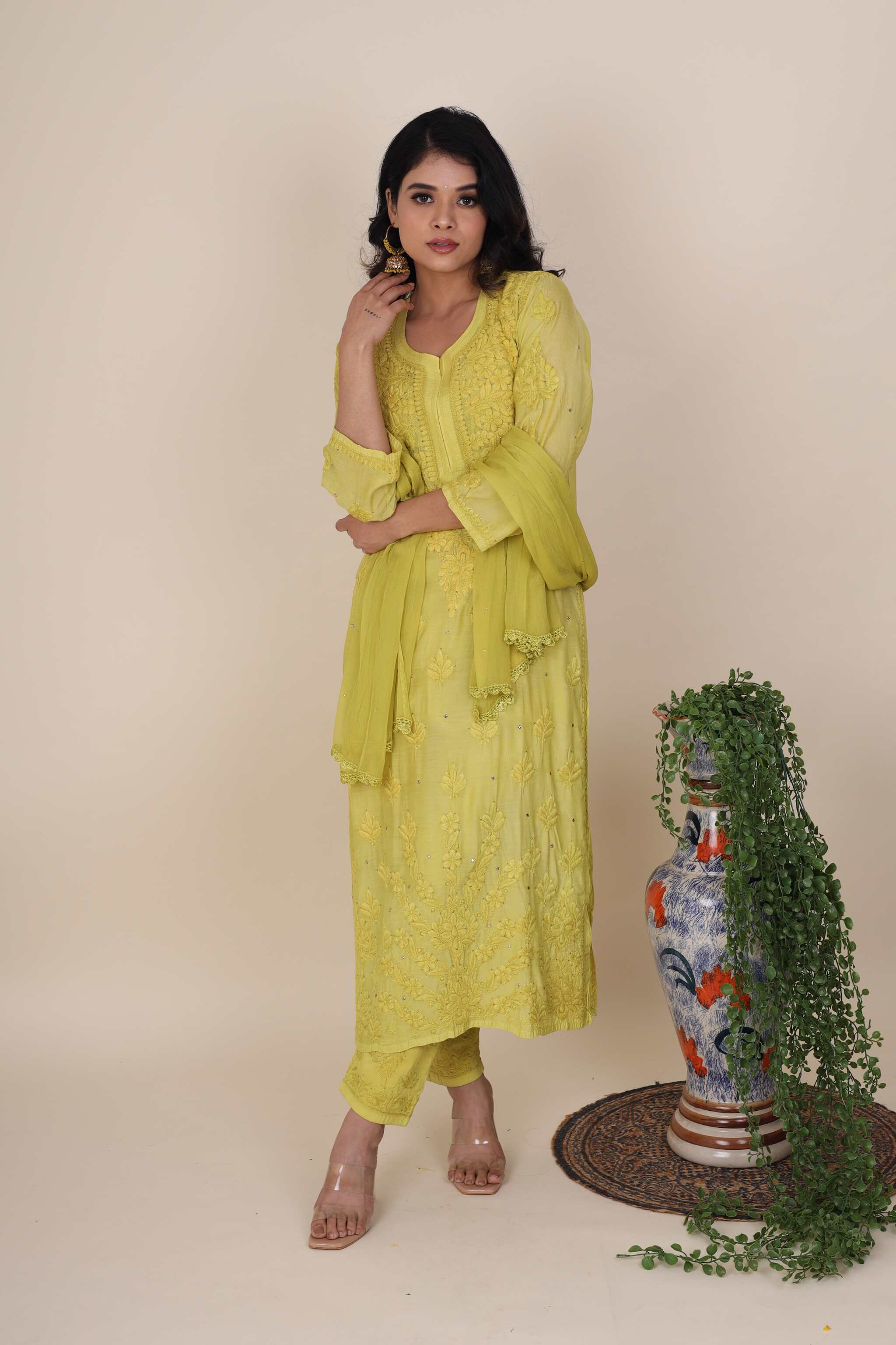 Woman in a Gulaabo Lime Green Kurta Set standing next to a decorative vase and plant on a beige background