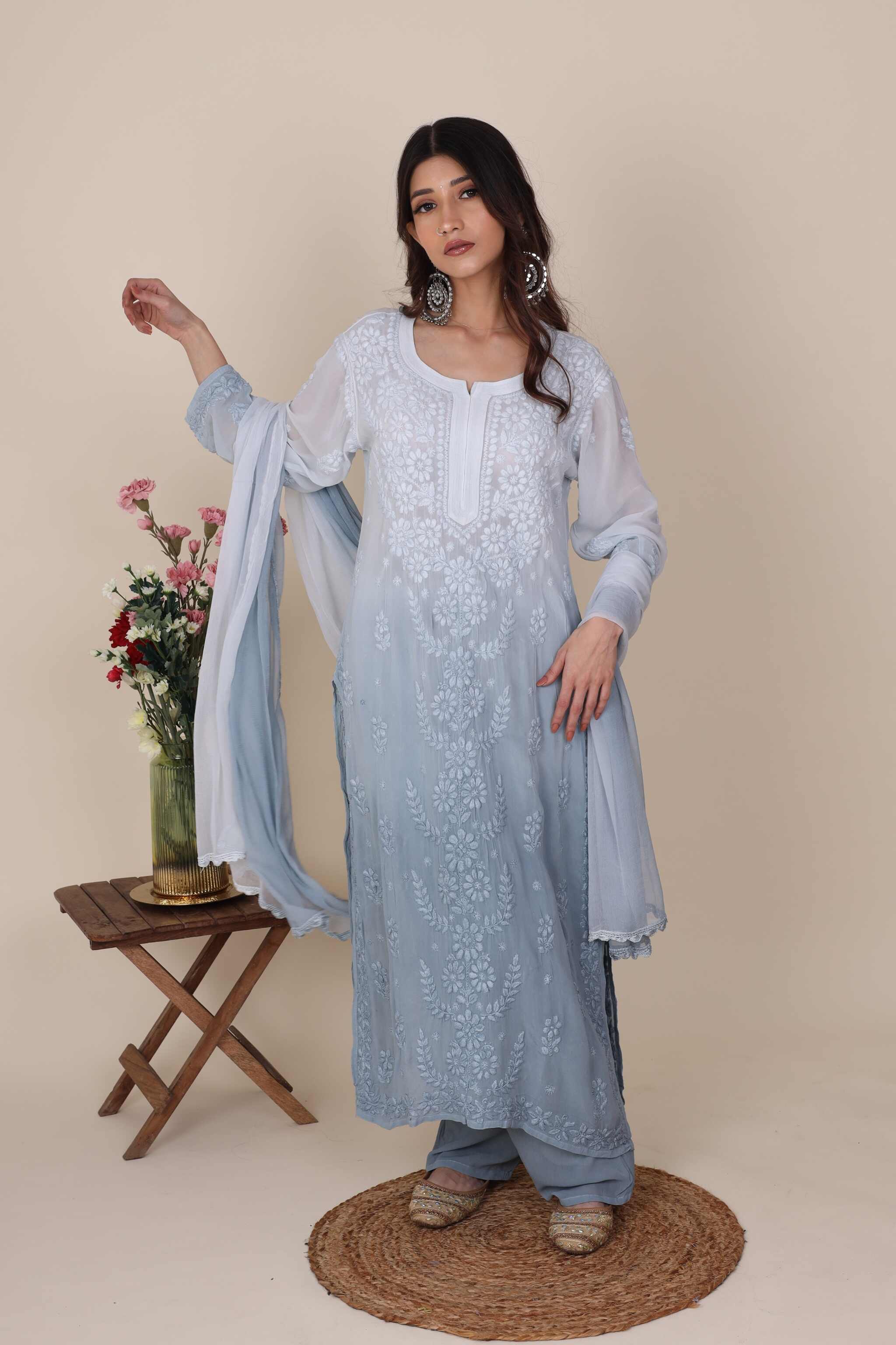 Woman wearing a light blue embroidered traditional Heer Opal Chikan Suit with a beige background
