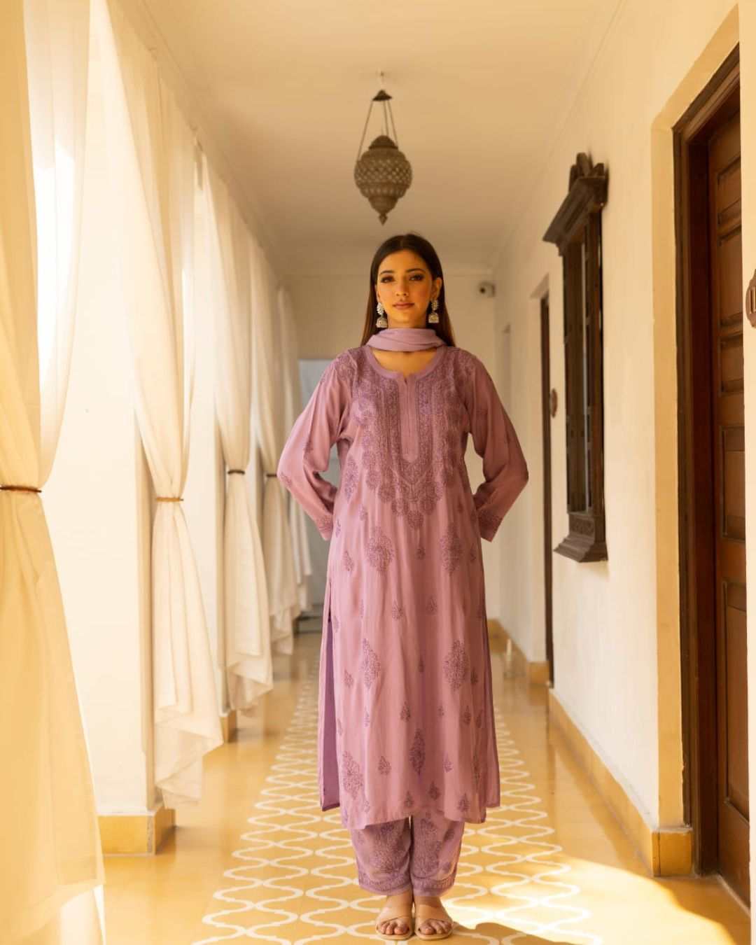 A women wearing purple chikankari suit and standing on a checked floor