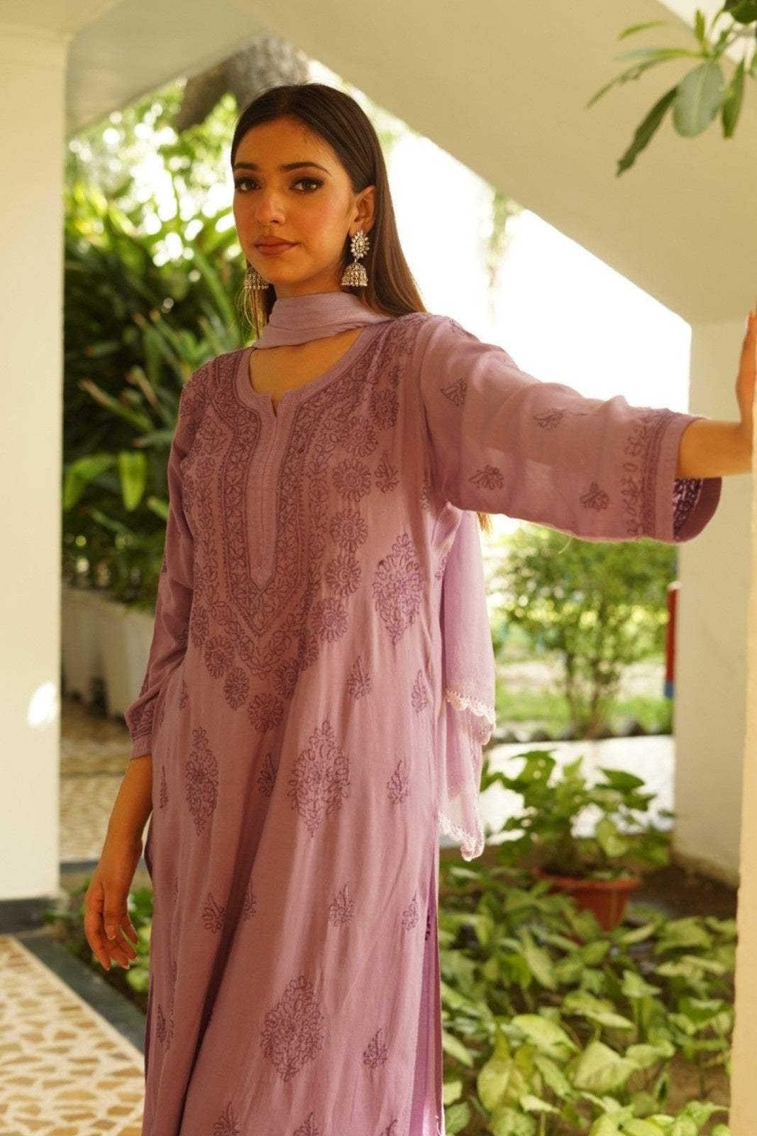 Woman wearing a pink traditional Mahek Purple Chikankari Suit with floral patterns in an outdoor setting.