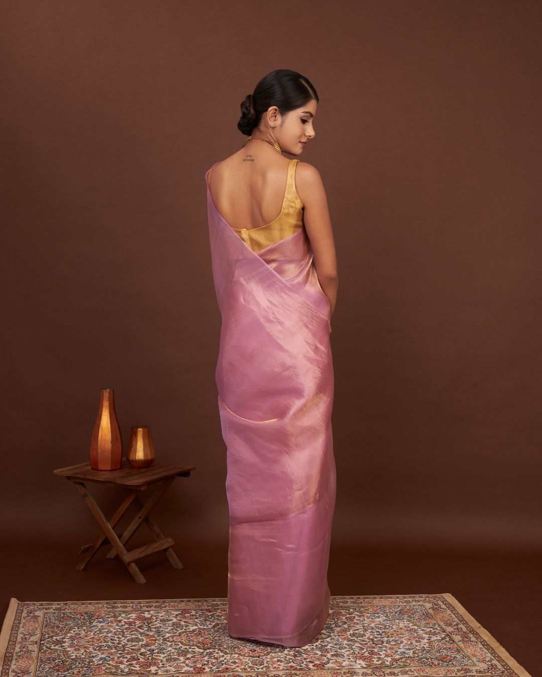 Side pose showcasing blouse design with tissue saree pleats.