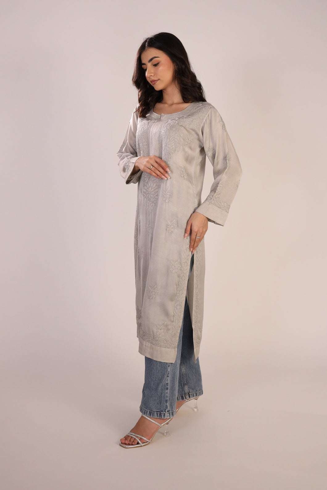 Woman wearing a long light gray chikankari kurta with a white background