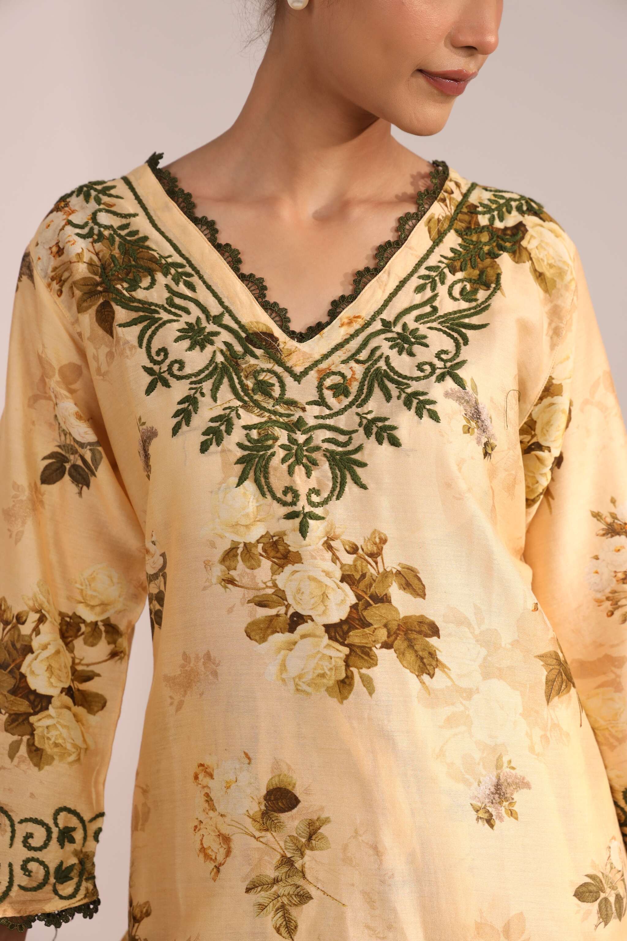 close up of chikankari embroidery on ladies co ord set yellow with floral patterns on a plain background