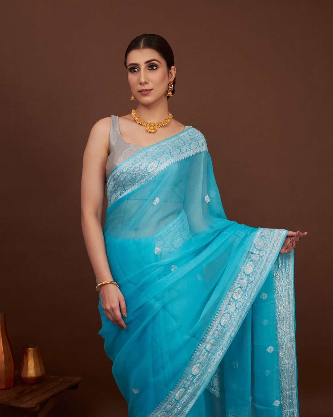 woman wearing a khadd georgette banarasi saree with silver zari standing in a elegant pose in dark background
