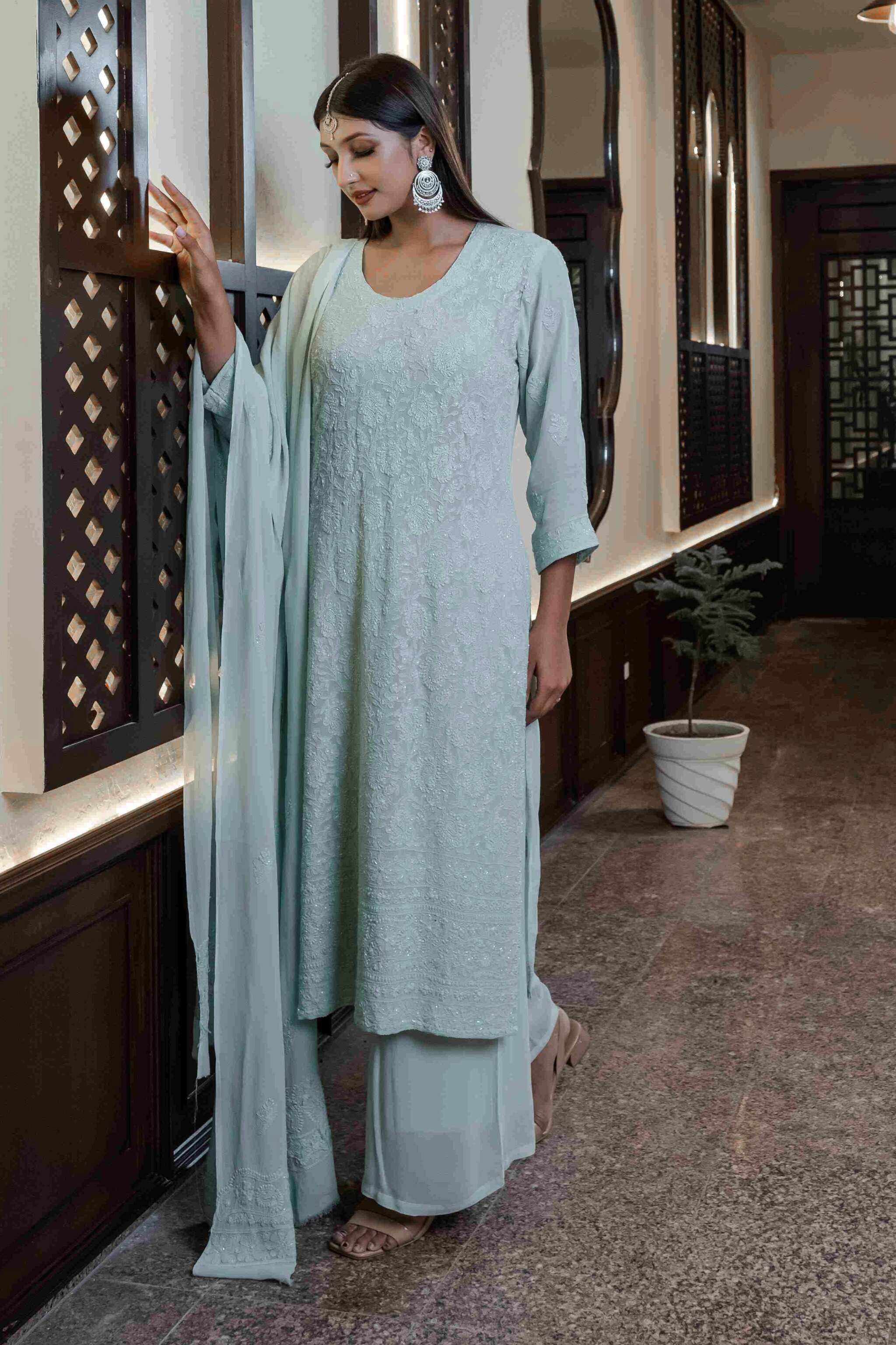 Woman in a light green traditional chikankari kurta set standing in an indoor setting.