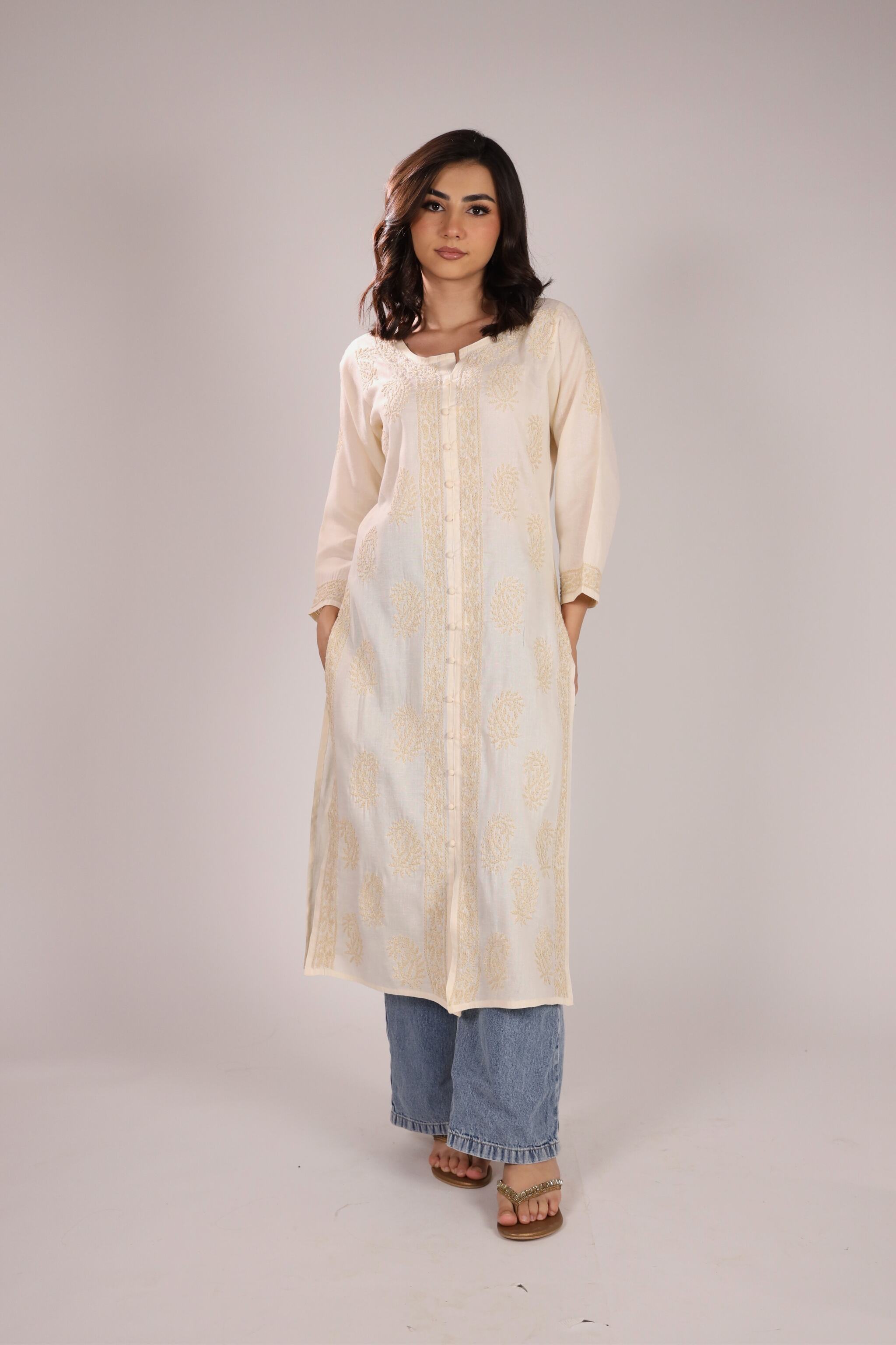 A women wearing a chikankari kurta in light yellow colour with plain background