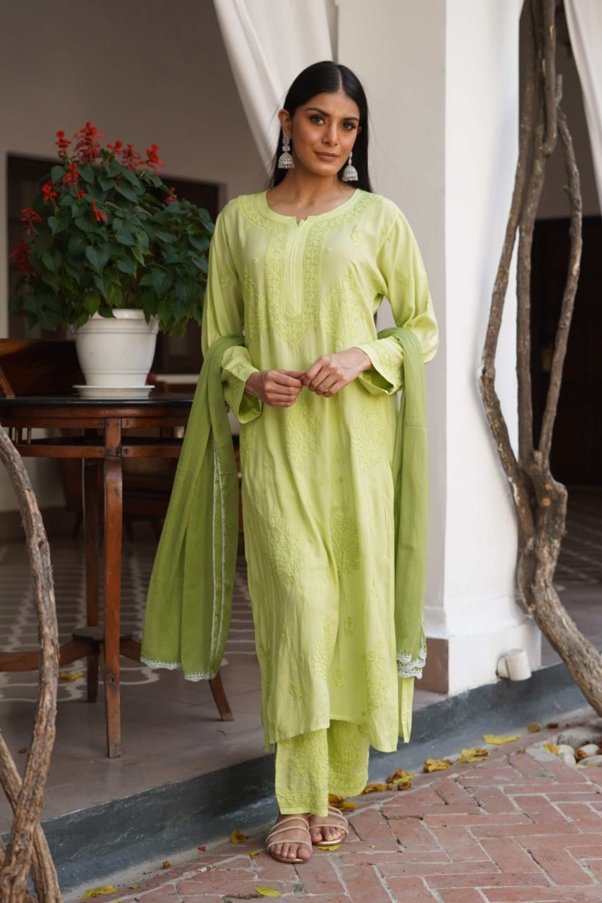 Woman in a light green traditional chikan kurta set standing outdoors.