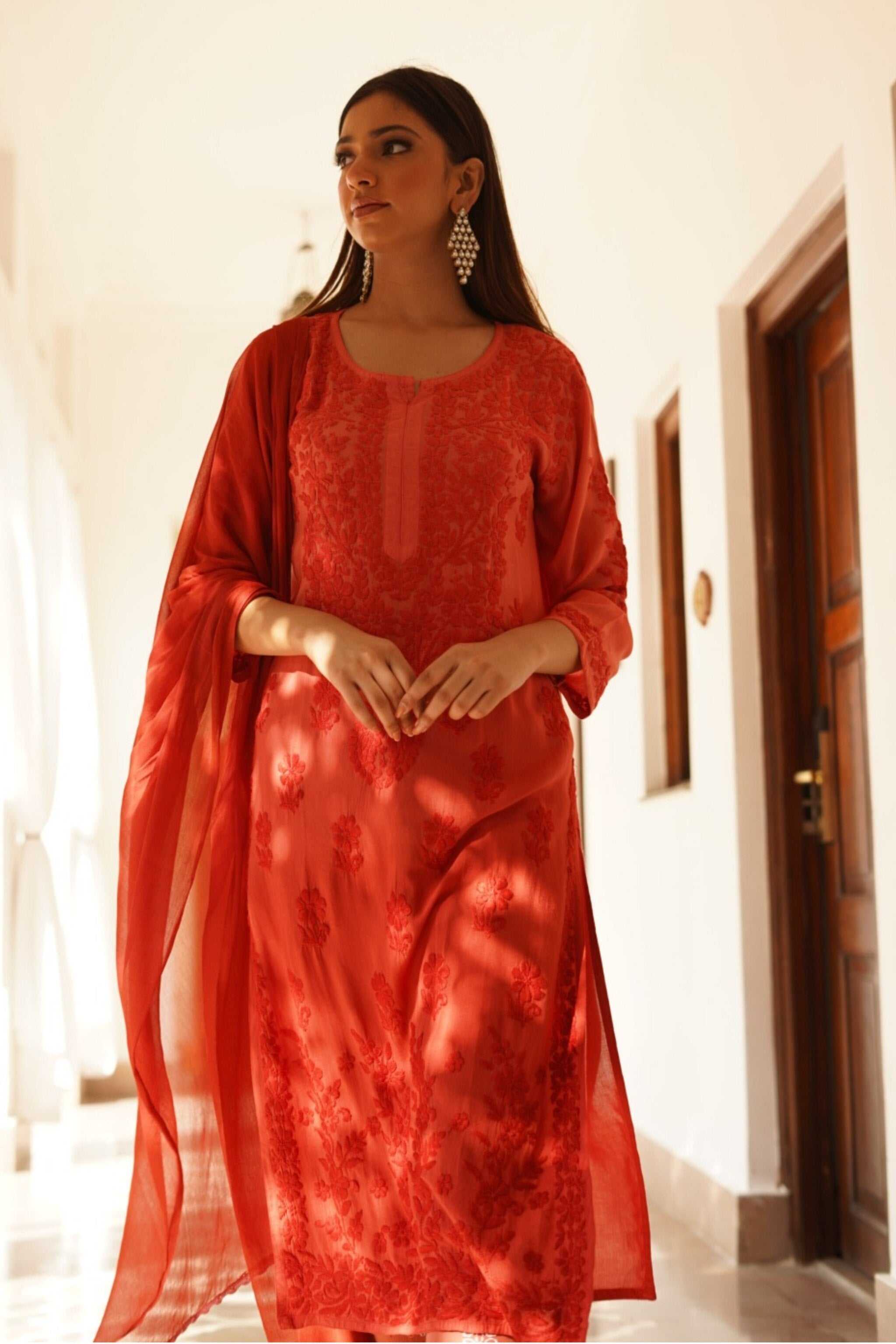 Woman wearing a red chikan kurta set patterned dress in an indoor setting