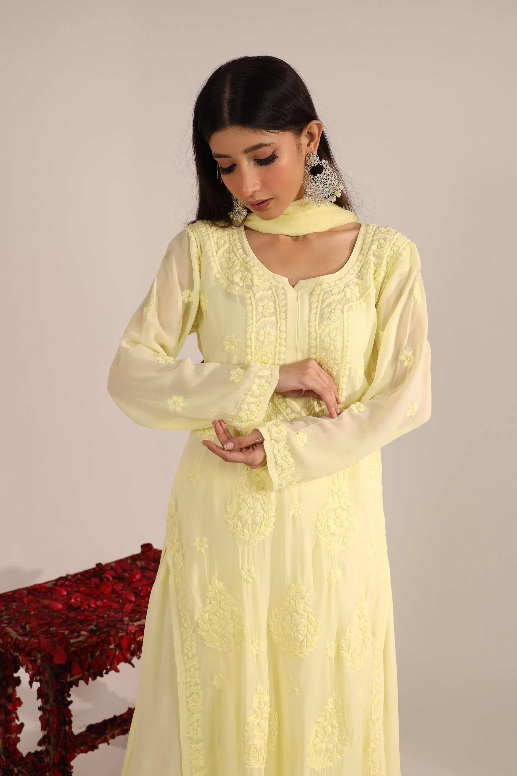 Woman wearing a light yellow viscose georgette chikankari suit with details against a plain background