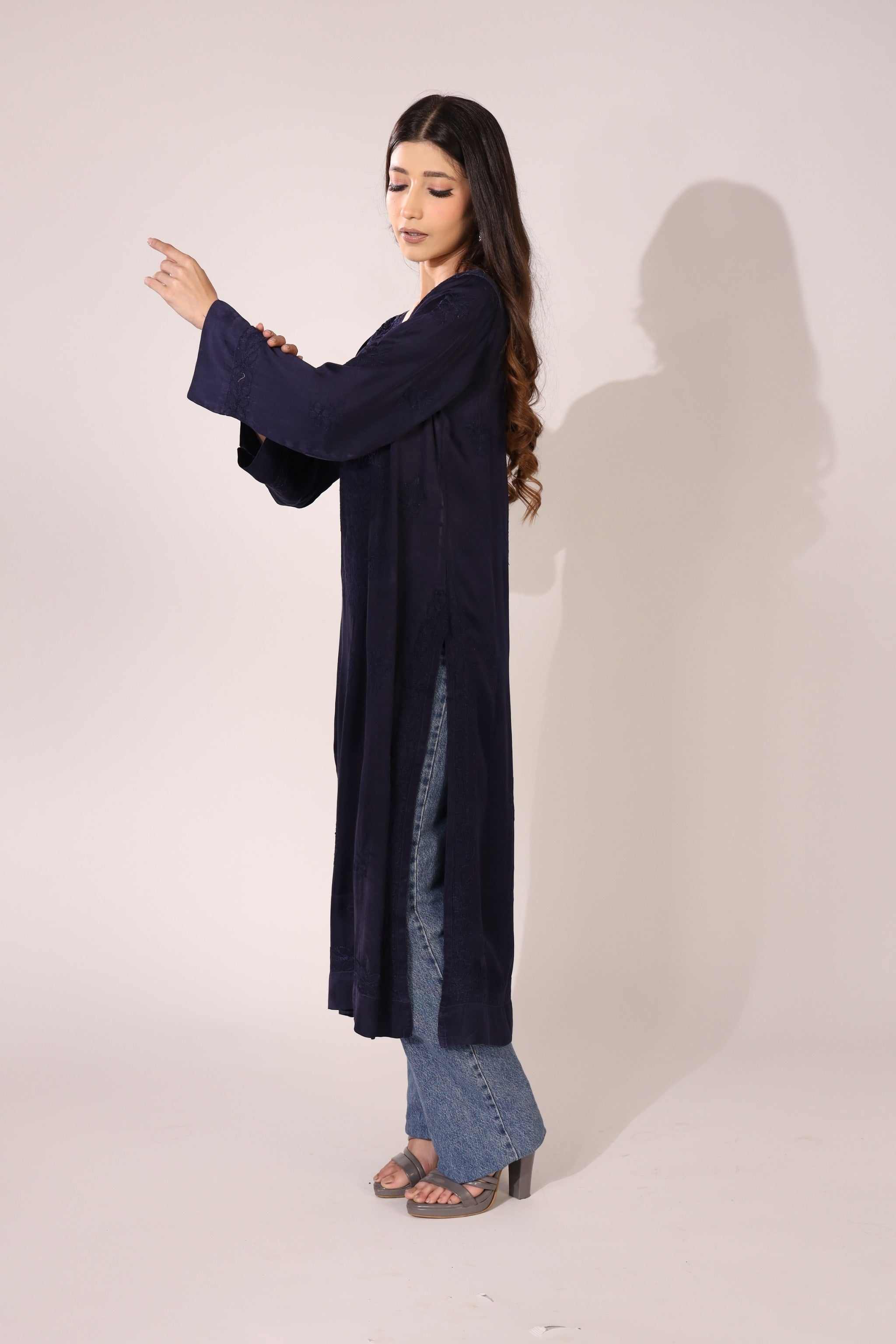 Woman wearing a long dark blue straight lucknowi kurta over jeans on a white background