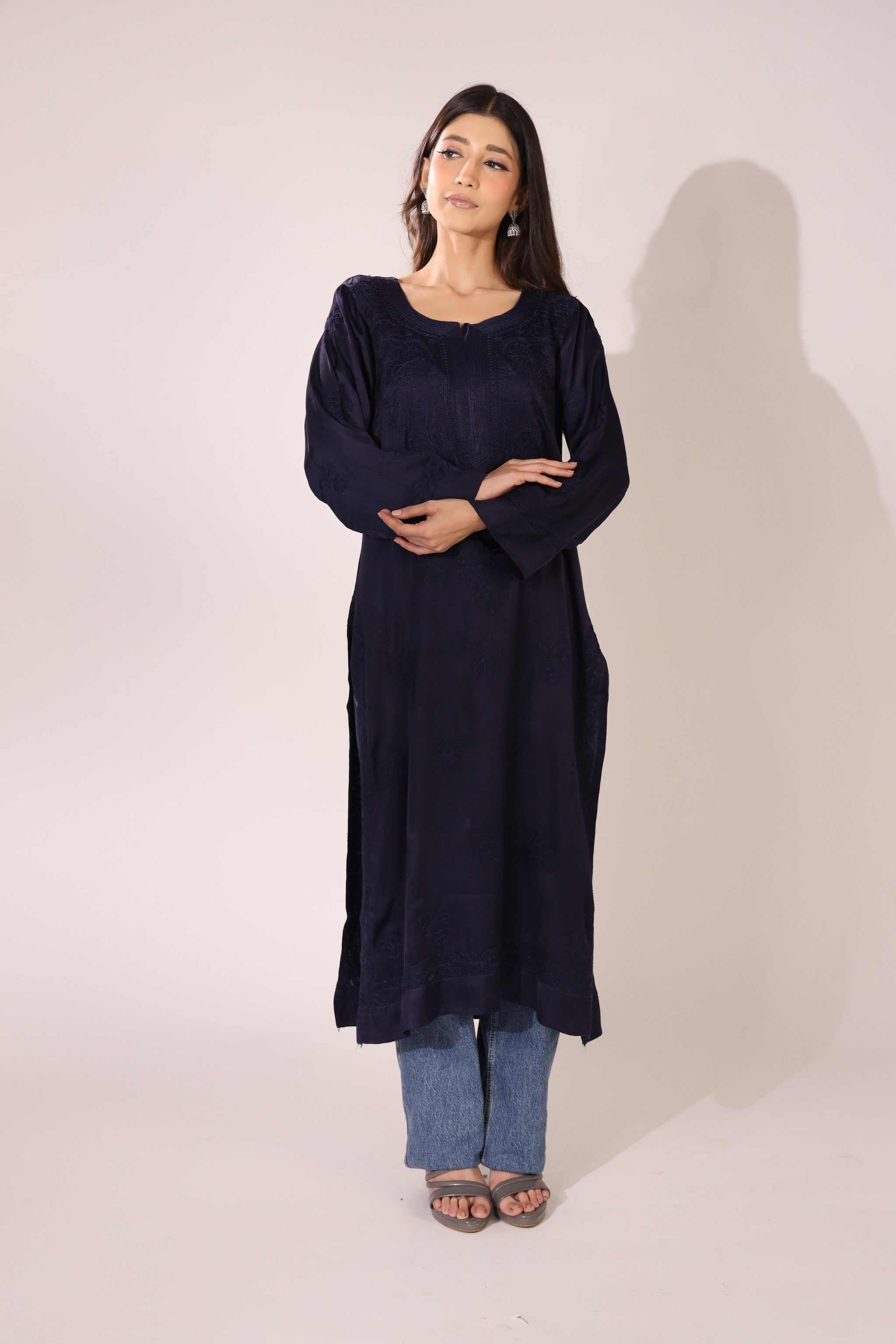 Woman wearing a dark blue lucknowi kurti with blue jeans on a white background